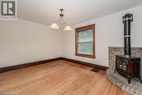 Hardwood flooring, wood-burning stove with brick surround, single window with wood trim, and a two-light ceiling fixture - 275 Main Street, Cambridge, ON 