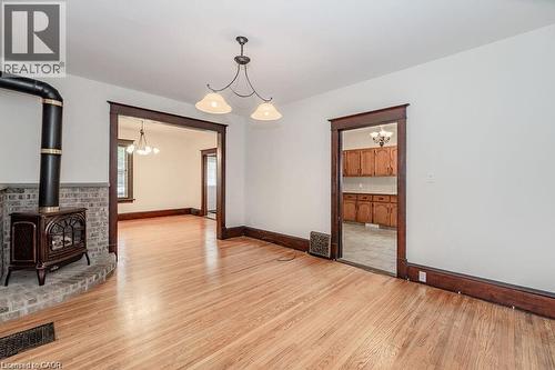 Hardwood flooring, cast iron stove with brick surround, traditional wood trim, and two-light pendant fixture - 275 Main Street, Cambridge, ON 