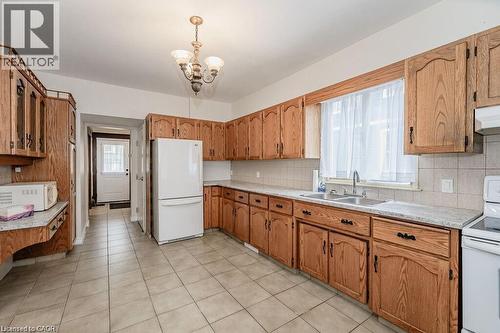 Kitchen featuring extensive wood cabinetry, tile flooring, a double basin stainless steel sink, and light-colored countertops - 275 Main Street, Cambridge, ON 