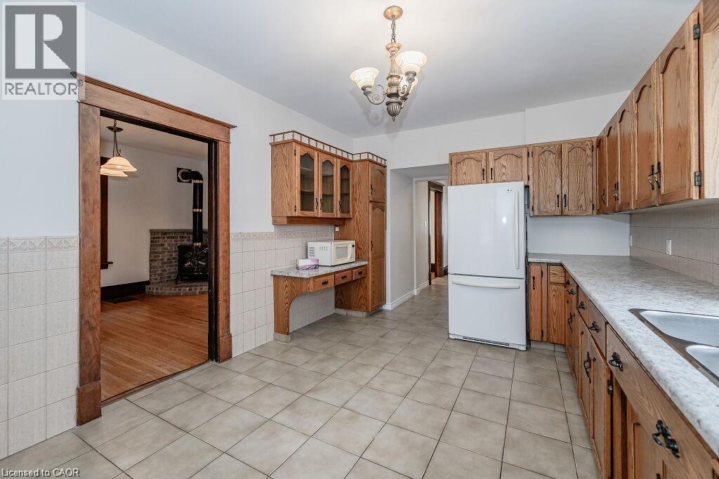 Kitchen featuring wood-finish cabinetry, tile flooring, and laminate countertops - 275 Main Street, Cambridge, ON
