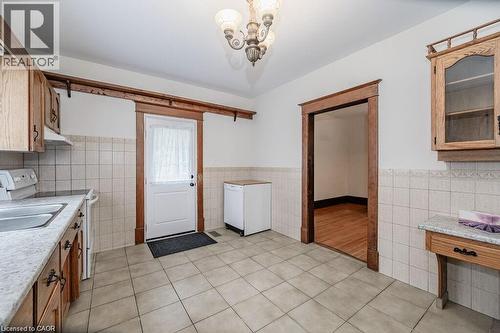 Tile flooring, wood cabinetry, stone-finish countertops, ceramic tile backsplash, and a decorative chandelier - 275 Main Street, Cambridge, ON 