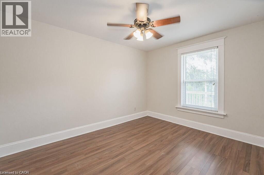 Wood-finish flooring, neutral wall tones, white trim, window with blinds, and a ceiling fan with integrated lighting - 275 Main Street, Cambridge, ON