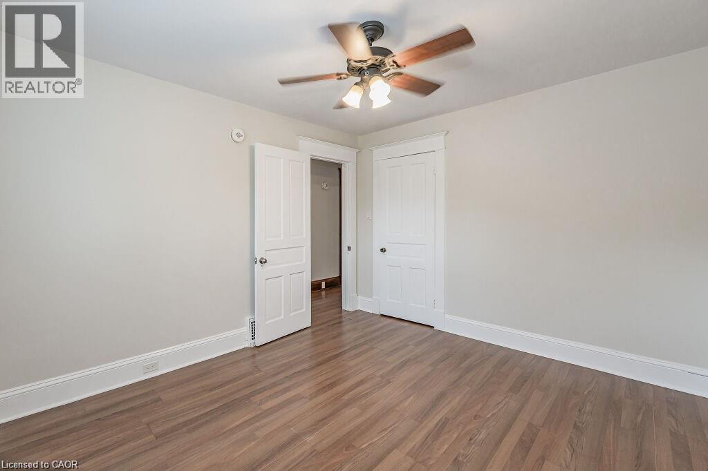 Wood-finish flooring, white trim, paneled doors, and a ceiling fan with light fixture - 275 Main Street, Cambridge, ON