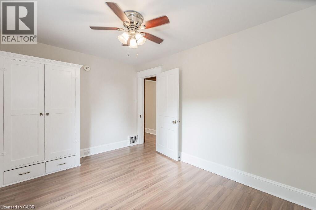 Wood-finish flooring, built-in storage with drawers, ceiling fan with integrated lighting, and a white paneled door - 275 Main Street, Cambridge, ON