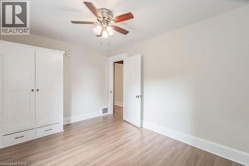 Wood-finish flooring, built-in storage with drawers, ceiling fan with integrated lighting, and a white paneled door - 275 Main Street, Cambridge, ON 
