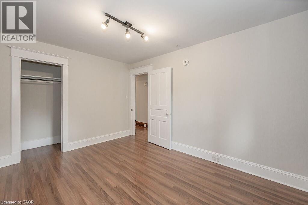 Wood-finish flooring with white trim, a closet with hanging rods, a white paneled door, and track lighting - 275 Main Street, Cambridge, ON
