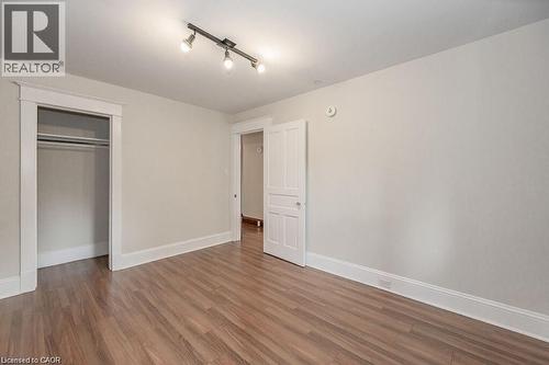 Wood-finish flooring with white trim, a closet with hanging rods, a white paneled door, and track lighting - 275 Main Street, Cambridge, ON 