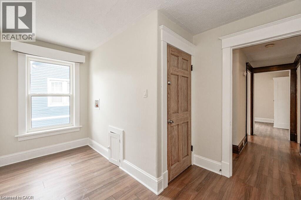 Wood-finish flooring throughout, white trim, and a paneled interior door - 275 Main Street, Cambridge, ON