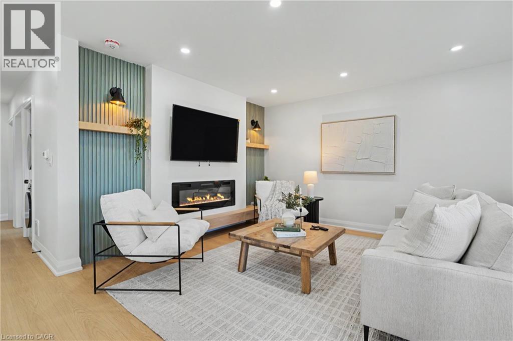 Recessed lighting illuminates the living space, featuring wood-finish flooring and a wall-mounted electric fireplace - 311 East 14Th Street, Hamilton, ON