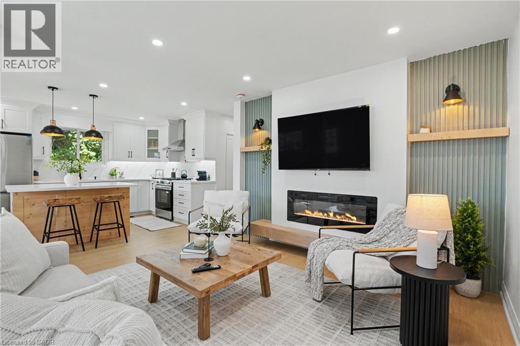 Open-concept living space featuring wood-finish flooring, recessed lighting, and a modern linear electric fireplace - 311 East 14Th Street, Hamilton, ON