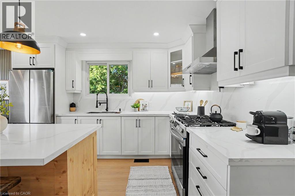 Modern kitchen featuring white shaker cabinetry, stainless steel appliances, white countertops, and wood-finish flooring - 311 East 14Th Street, Hamilton, ON