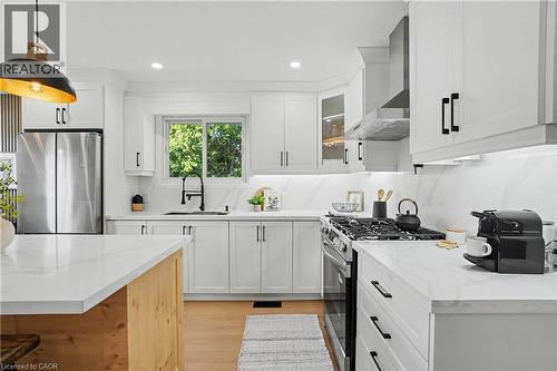 Modern kitchen featuring white shaker cabinetry, stainless steel appliances, white countertops, and wood-finish flooring - 311 East 14Th Street, Hamilton, ON 