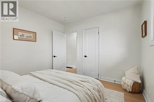 Bright secondary bedroom featuring hardwood flooring, white six-panel doors, and neutral wall finishes - 311 East 14Th Street, Hamilton, ON 