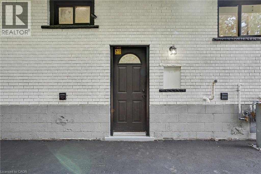 Exterior featuring white brick and concrete block construction - 311 East 14Th Street, Hamilton, ON