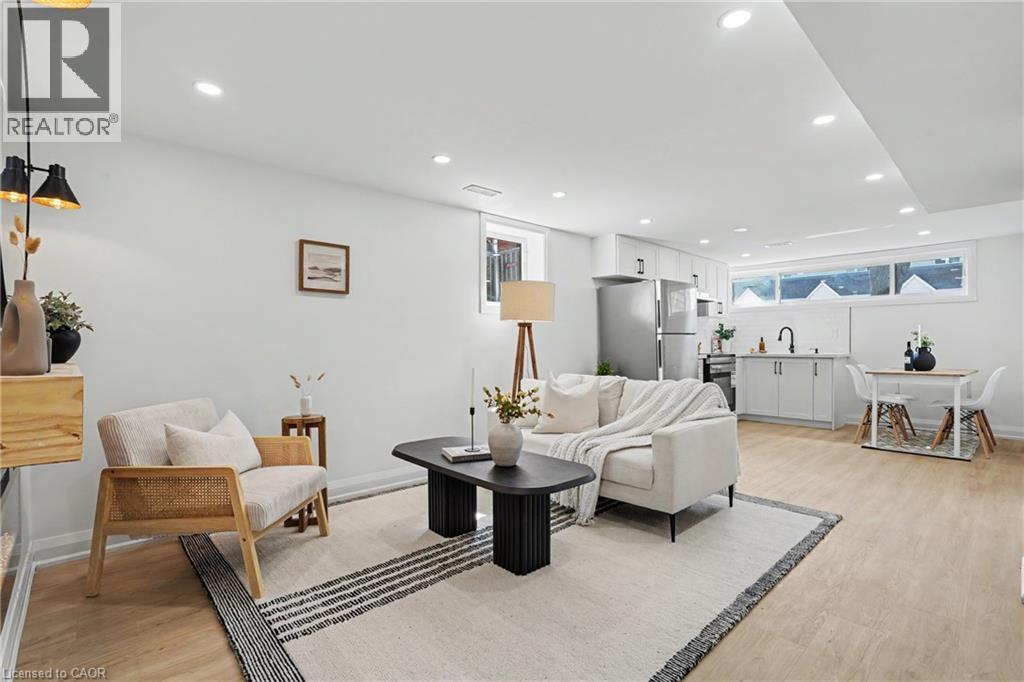 Recessed ceiling lighting, light wood-finish flooring, white walls, and a built-in kitchen area with white cabinetry - 311 East 14Th Street, Hamilton, ON