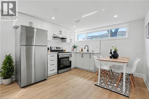 White shaker cabinetry, stainless steel appliances, wood-finish flooring, recessed lighting, and a subway tile backsplash - 311 East 14Th Street, Hamilton, ON 