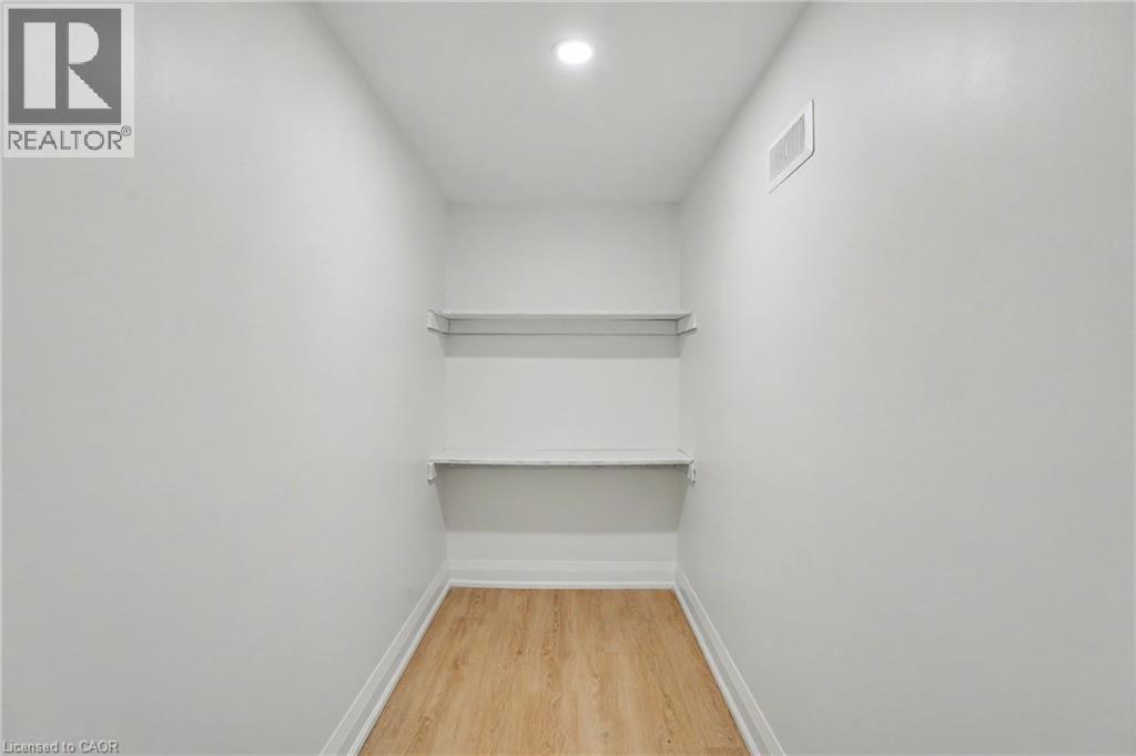 Recessed ceiling lighting illuminates white walls, wood-finish flooring, and built-in shelving - 311 East 14Th Street, Hamilton, ON