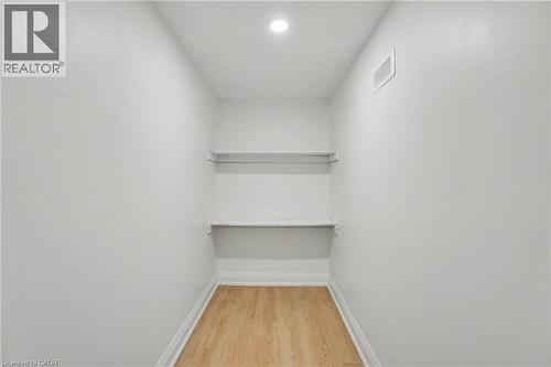 Recessed ceiling lighting illuminates white walls, wood-finish flooring, and built-in shelving - 311 East 14Th Street, Hamilton, ON 