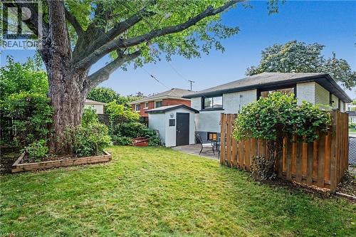 Expansive grassy yard with mature tree, raised garden bed, and wood privacy fencing - 311 East 14Th Street, Hamilton, ON 