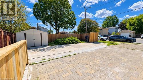 Expansive paved driveway with permeable brick pavers, mature landscaping with established trees, detached storage shed, and wooden privacy fencing throughout the property - 76 Avenue Road, Cambridge, ON 