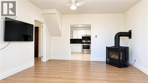 Wood-finish flooring throughout, featuring an open-concept layout, a ceiling fan, and a freestanding fireplace - 76 Avenue Road, Cambridge, ON 