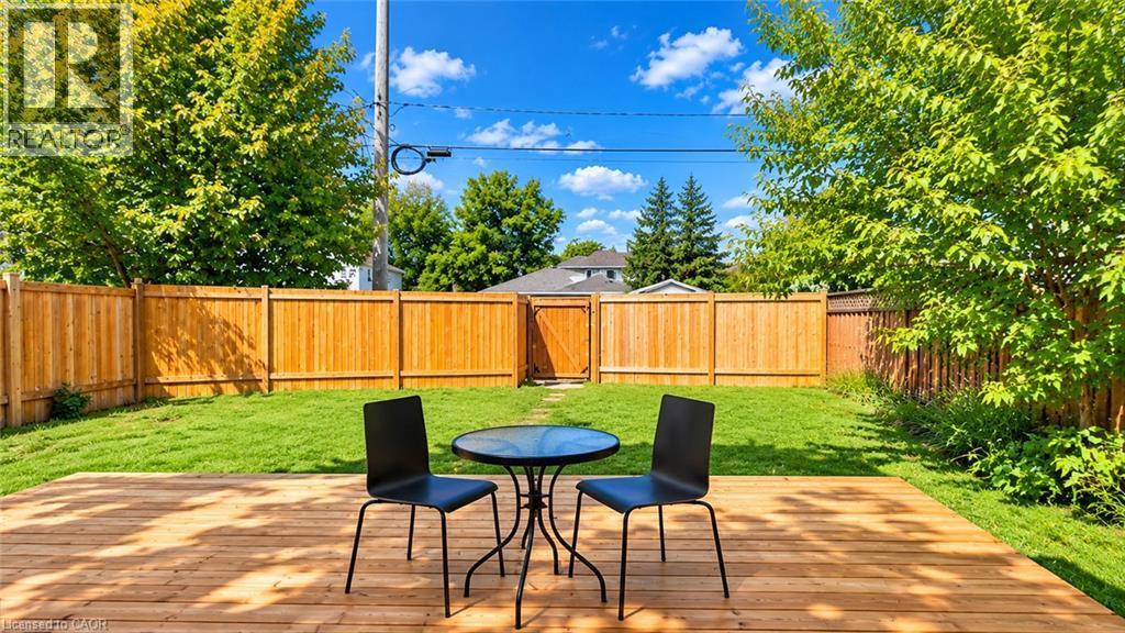 Expansive backyard featuring a wood deck, manicured lawn, and mature trees - 76 Avenue Road, Cambridge, ON