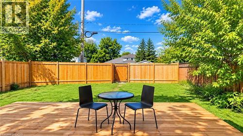 Expansive backyard featuring a wood deck, manicured lawn, and mature trees - 76 Avenue Road, Cambridge, ON 