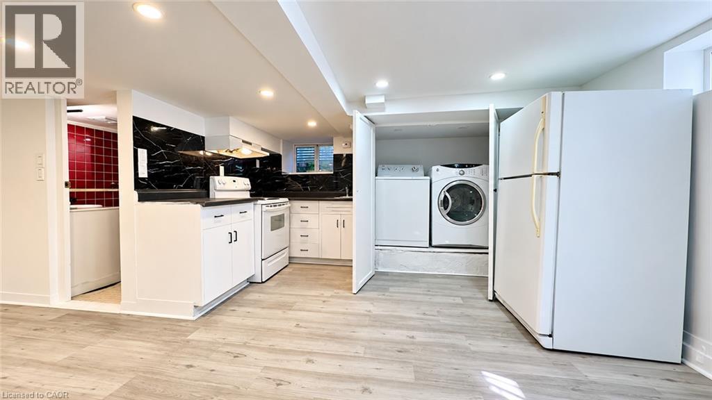 Kitchenette featuring white cabinetry, black countertops, and a black marble-effect backsplash - 76 Avenue Road, Cambridge, ON
