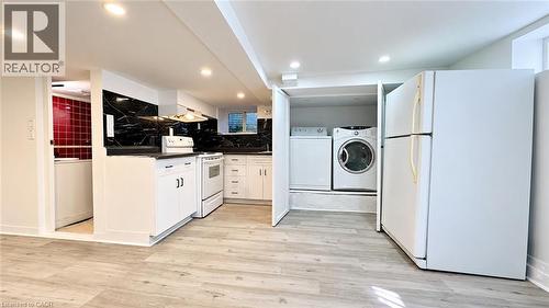 Kitchenette featuring white cabinetry, black countertops, and a black marble-effect backsplash - 76 Avenue Road, Cambridge, ON 