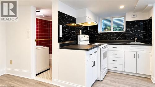 Kitchenette with white cabinetry, black countertops, and a black and white patterned backsplash - 76 Avenue Road, Cambridge, ON 