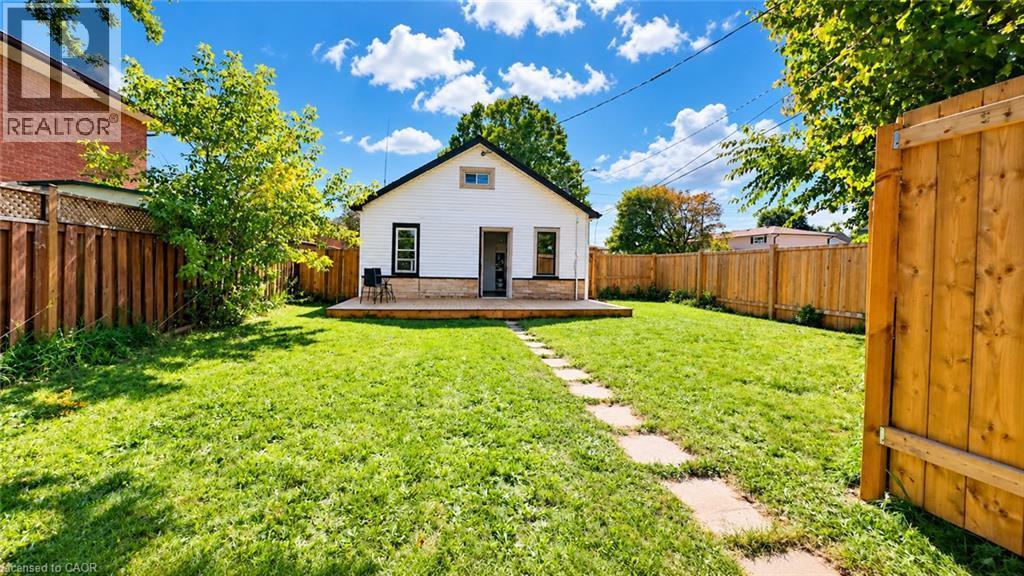 Expansive backyard featuring a manicured lawn, a wooden deck, and a stone-paver pathway - 76 Avenue Road, Cambridge, ON