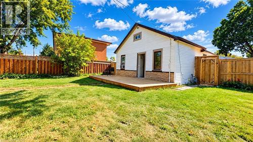 Expansive backyard with a wooden fence, featuring a ground-level deck, white siding, and a rear entry - 76 Avenue Road, Cambridge, ON 