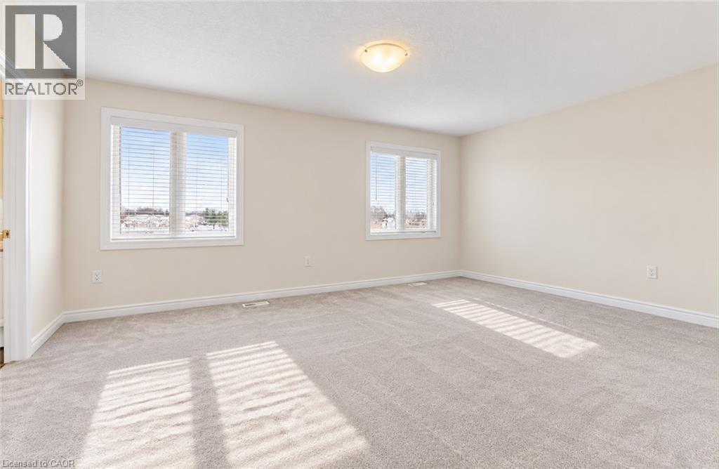 Spacious room with plush carpeting, neutral wall finishes, multiple windows, and a flush mount ceiling light - 61 Duckworth Road, Cambridge, ON