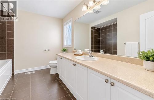 Bathroom with brown tile flooring, a white vanity with a light-colored countertop, and a shower-tub combination with brown tile surround - 61 Duckworth Road, Cambridge, ON 
