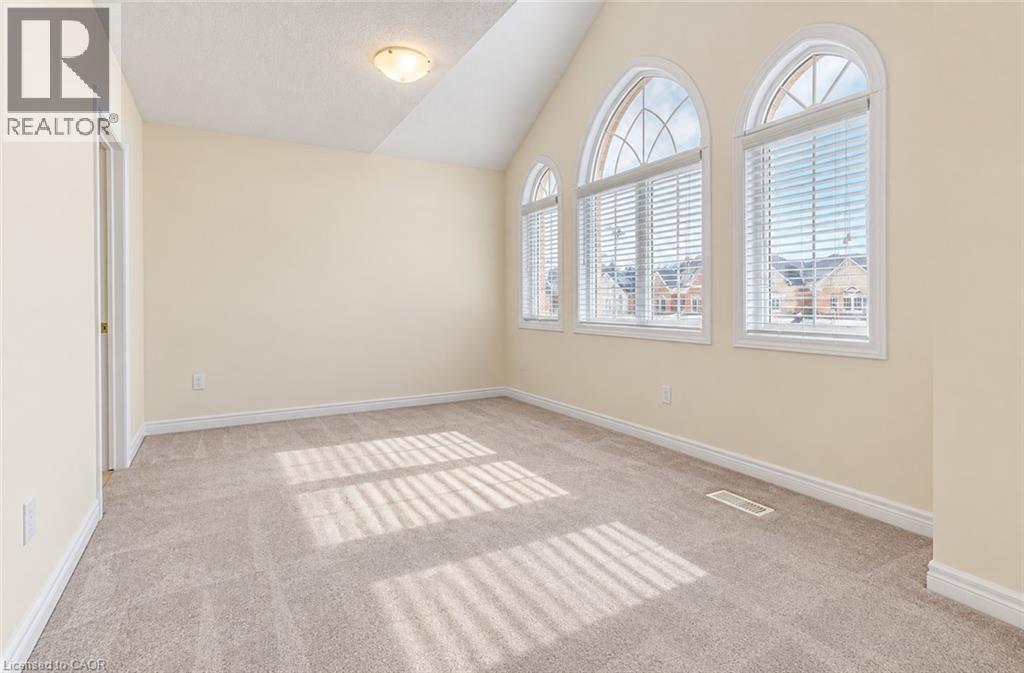 Three arched windows with blinds, pitched ceiling, neutral wall paint, and light-toned carpeting - 61 Duckworth Road, Cambridge, ON
