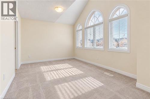 Three arched windows with blinds, pitched ceiling, neutral wall paint, and light-toned carpeting - 61 Duckworth Road, Cambridge, ON 