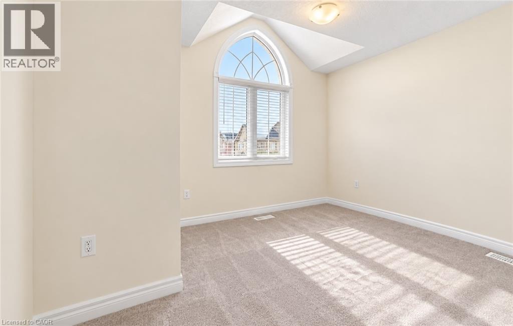 Arch-top window with blinds, vaulted ceiling, flush-mount ceiling light, and neutral wall tones - 61 Duckworth Road, Cambridge, ON