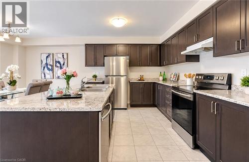 Kitchen featuring dark wood-finish cabinetry, light speckled countertops, stainless steel appliances, and tile flooring - 61 Duckworth Road, Cambridge, ON 