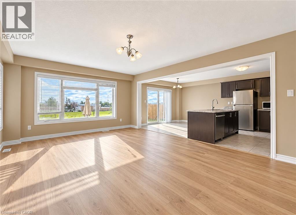 Spacious living area featuring wood-finish flooring, a large picture window, and a chandelier - 61 Duckworth Road, Cambridge, ON