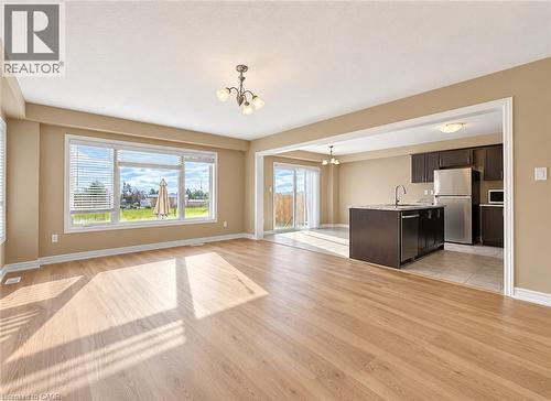 Spacious living area featuring wood-finish flooring, a large picture window, and a chandelier - 61 Duckworth Road, Cambridge, ON 