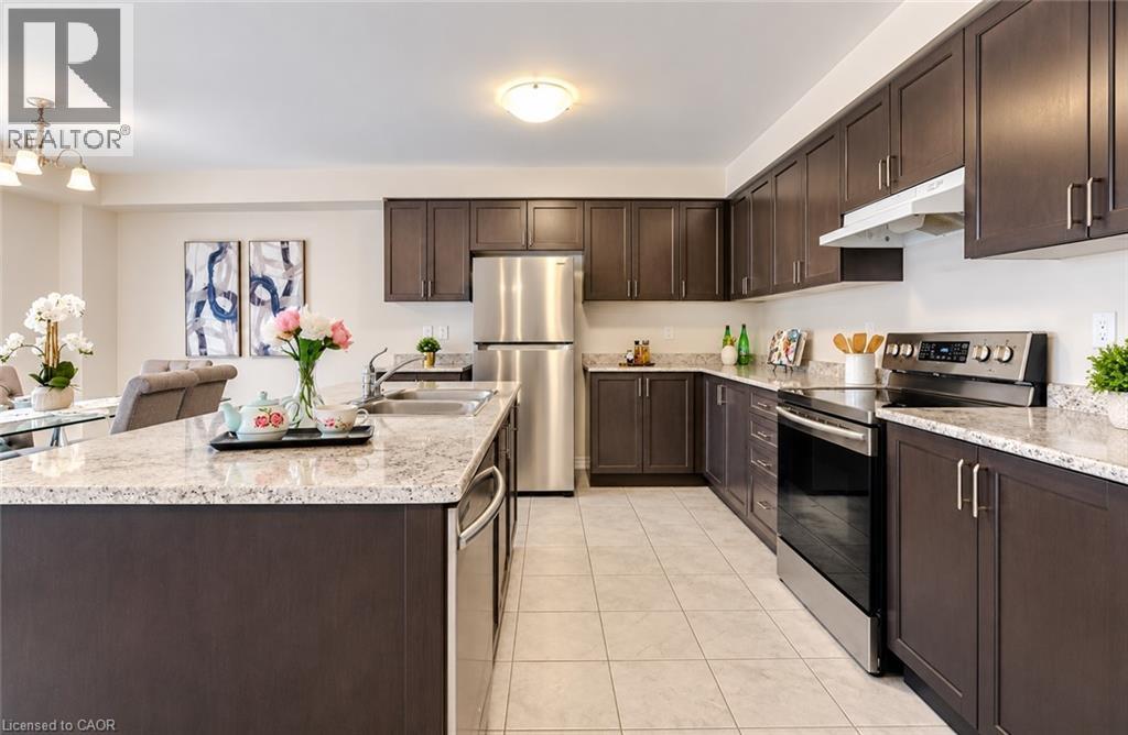 Kitchen featuring dark wood-finish cabinetry, light speckled countertops, stainless steel appliances, and tile flooring - 61 Duckworth Road, Cambridge, ON