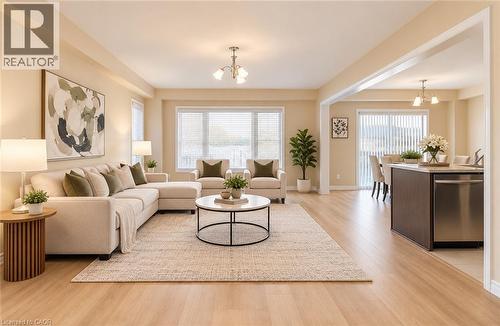 Expansive open-concept living area featuring wood-finish flooring, recessed lighting, large windows with blinds, and a kitchen island with integrated stainless steel dishwasher - 61 Duckworth Road, Cambridge, ON 