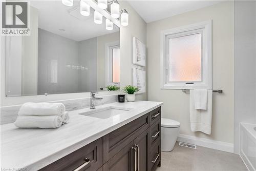 Main bathroom on main floor - vanity with a white quartz countertop and undermount sink, a rectangular mirror, and an overhead light fixture - 46 Esther Avenue, Cambridge, ON 