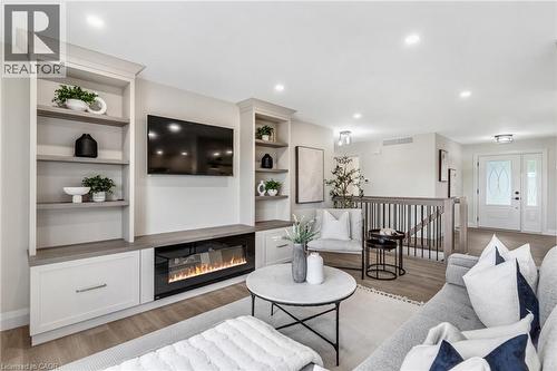 Integrated built-in shelving, electric fireplace with media console, wood-finish flooring, recessed lighting, and double entry doors - 46 Esther Avenue, Cambridge, ON 