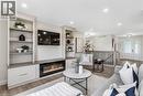 Integrated built-in shelving, electric fireplace with media console, wood-finish flooring, recessed lighting, and double entry doors - 46 Esther Avenue, Cambridge, ON 