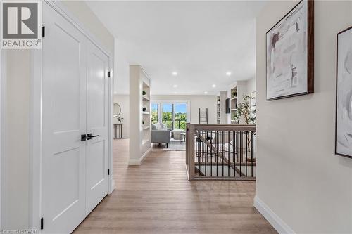 Wood-finish flooring throughout, white paneled doors with black hardware, recessed lighting, and a staircase with a wood handrail and black metal balusters - 46 Esther Avenue, Cambridge, ON 