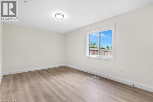 Neutral wall paint, wood-finish flooring, white trim, and a flush-mount ceiling light fixture - 46 Esther Avenue, Cambridge, ON 
