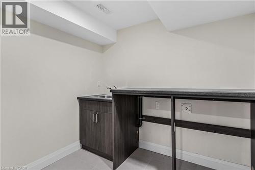 Built-in wood-finish cabinetry, stainless steel double-basin sink, and a dark countertop ready for washer and dryer to be installed - 46 Esther Avenue, Cambridge, ON 