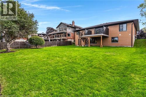 Expansive green lawn with mature trees and a wooden privacy fence. Two-tiered deck with walkout - 46 Esther Avenue, Cambridge, ON 