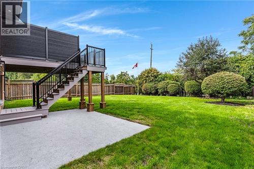 Expansive green lawn, wood fence, concrete patio, elevated deck with black railings, mature landscaping and walkout - 46 Esther Avenue, Cambridge, ON 
